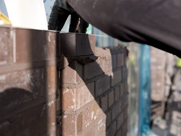 Brickwork at Cremer Street. Ground-bearing brick walls are one brick thick, laid in a garden wall bond; the walls to Nazrul Street have panels in basket-weave; set-back walls are in a custom brick with a fine ribbed texture.